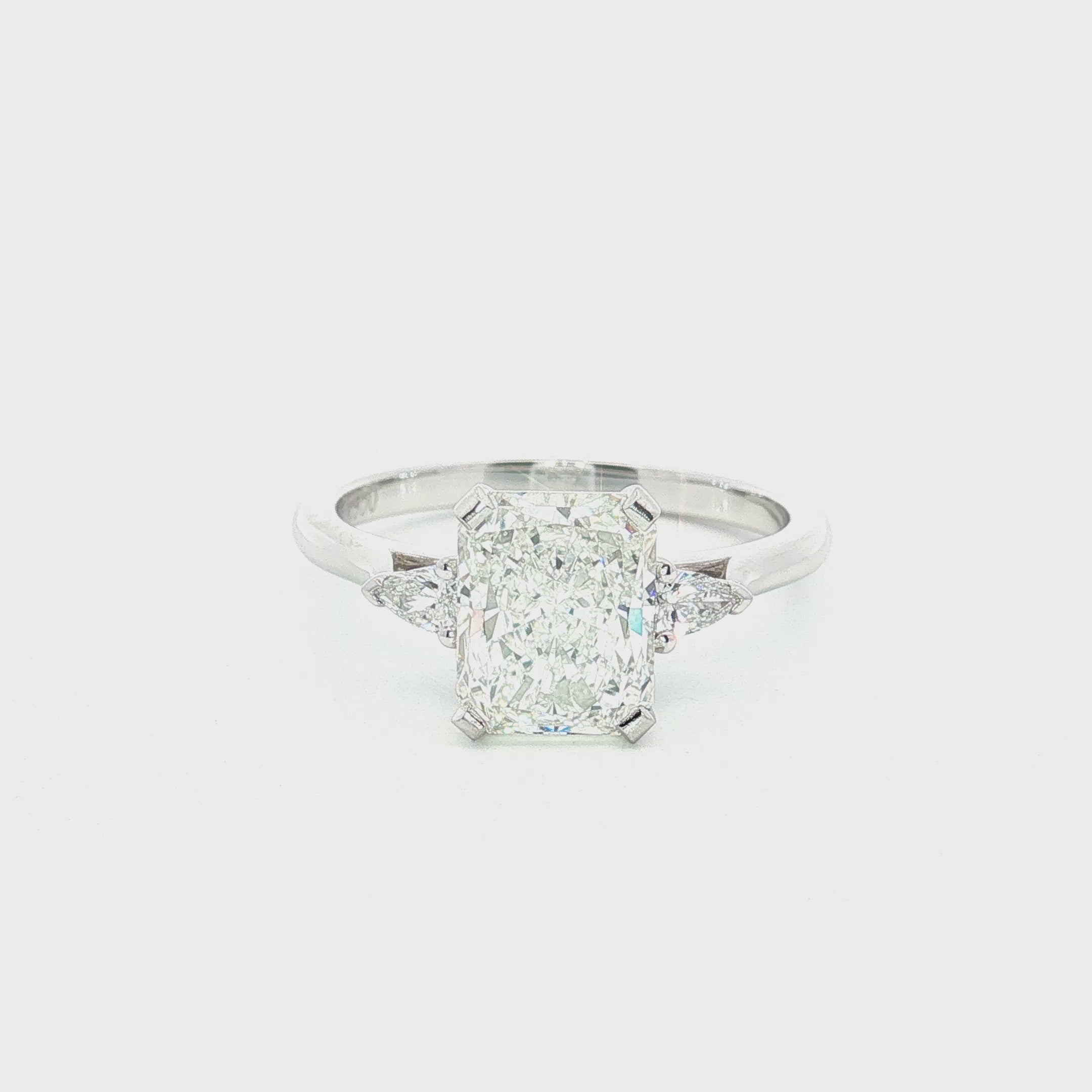 Platinum three-stone engagement ring featuring a 2.02ct radiant cut diamond with two pear cut diamond side stones.