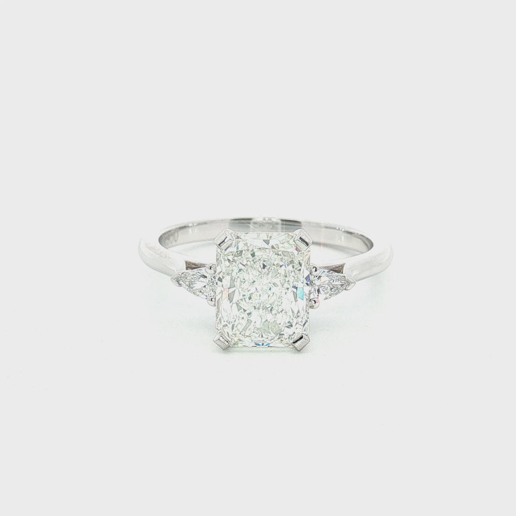 Platinum three-stone engagement ring featuring a 2.02ct radiant cut diamond with two pear cut diamond side stones.