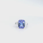 18ct white gold ring featuring a 6.99ct radiant cut tanzanite with two tapered baguette cut diamonds in a tiered three-stone setting.