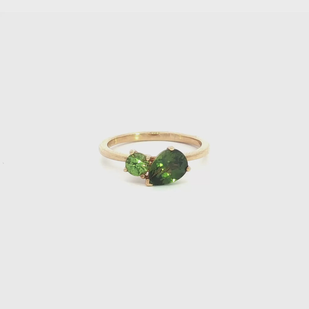 9ct yellow gold “Toi et Moi” ring featuring a 1.22ct pear cut and 0.32ct round green sapphire in angled claw settings with post and bezel collets.