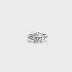 18ct white gold three stone diamond ring featuring a 2.17ct oval centre diamond with pear cut diamond side stones in tiered cap-and-claw settings.