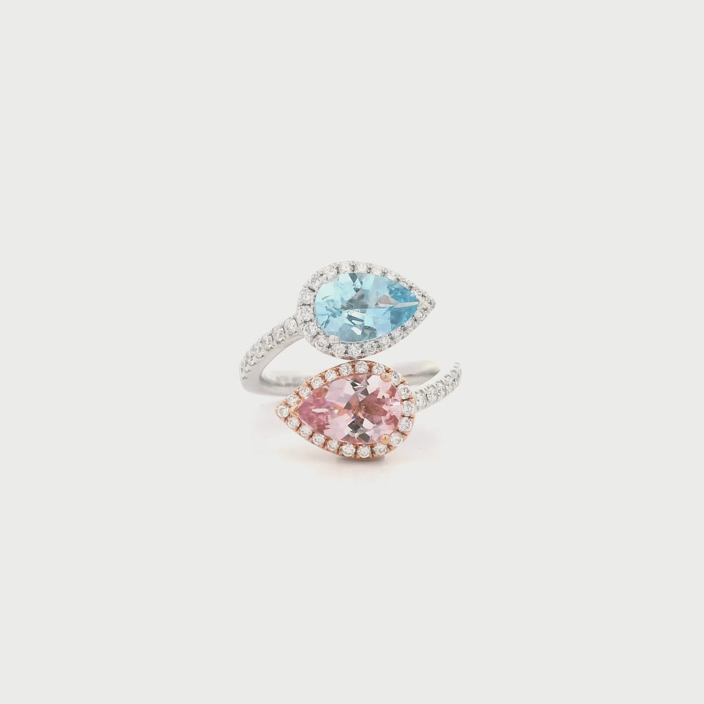 18ct white and rose gold ring featuring a cross-over design with pear-cut morganite and aquamarine gemstones surrounded by diamond halos and claw-set diamond shoulders.