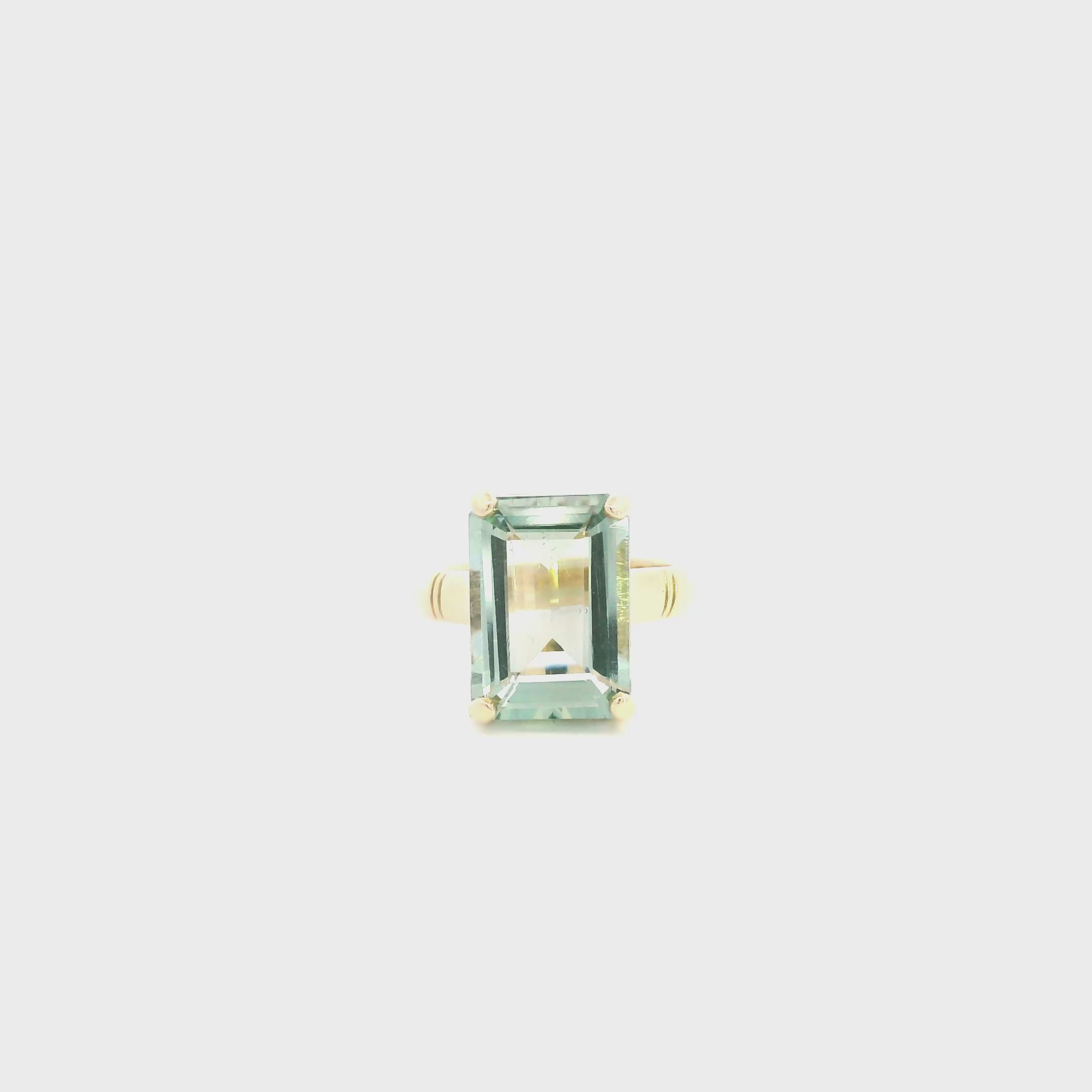 9ct yellow gold ring featuring a 14 x 10mm emerald cut green quartz in a four-claw setting with engraved shoulders.