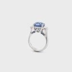 18ct white gold three stone ring featuring an 8.07ct cushion cut blue sapphire with cadillac cut diamond side stones and sapphire-diamond accents in the undercarriage.