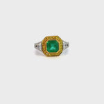 18ct ring featuring a 1.40ct square emerald-cut emerald with trapezoid side diamonds and a halo of yellow and white round brilliant cut diamonds.