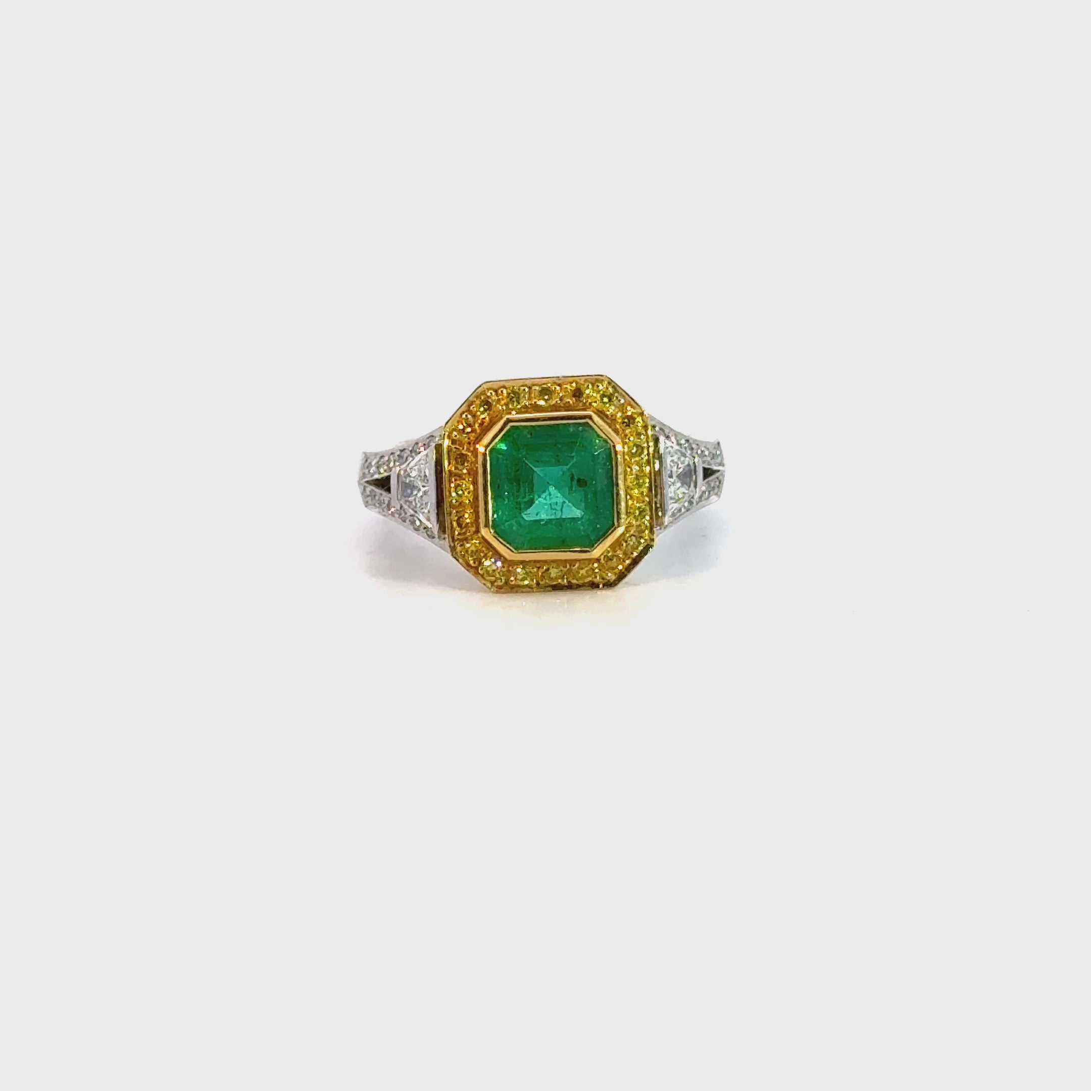 18ct ring featuring a 1.40ct square emerald-cut emerald with trapezoid side diamonds and a halo of yellow and white round brilliant cut diamonds.