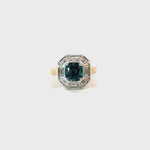 18ct yellow and white gold ring featuring a 1.88ct cushion cut greenish-blue tourmaline surrounded by baguette and round brilliant cut diamonds in an octagonal cluster design.