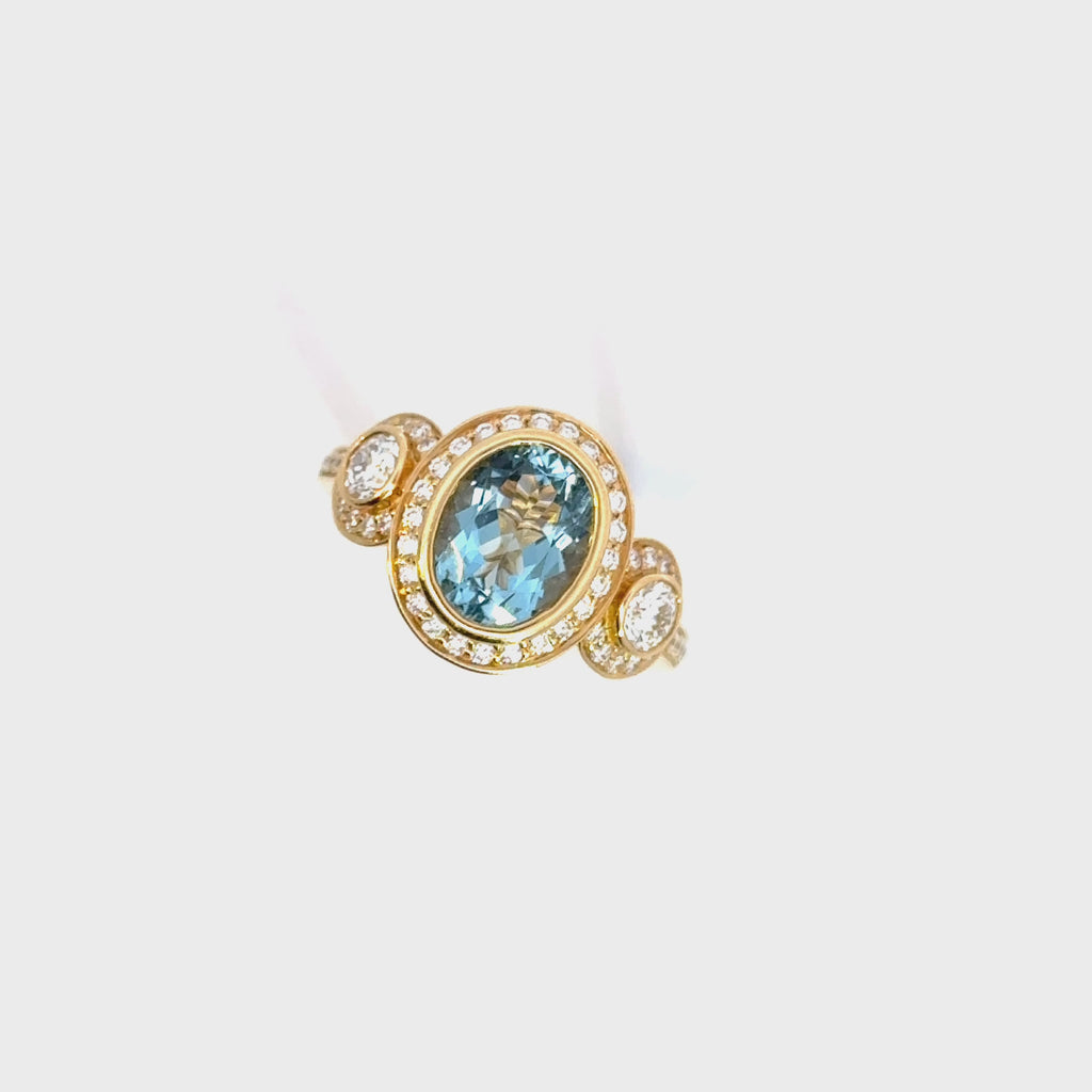 18ct yellow gold aquamarine and diamond ring featuring a 1.68ct oval aquamarine in a diamond halo bezel with side halos and bead-set diamond shoulders.