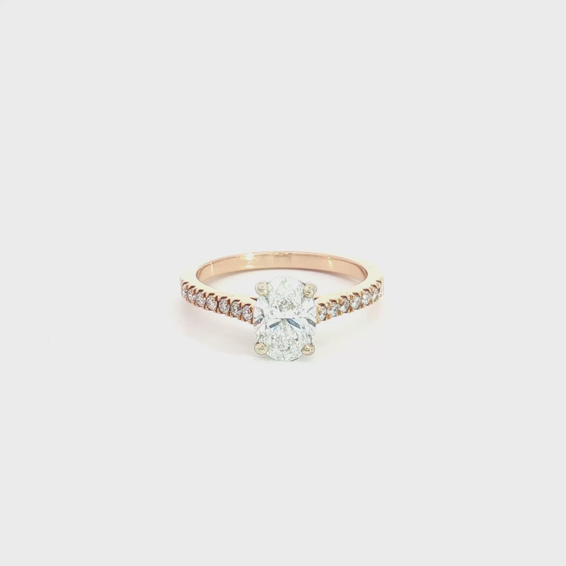 18ct rose and white gold diamond ring featuring a 1.02ct E/SI2 oval cut diamond in a white gold four-claw setting with diamond-set shoulders.