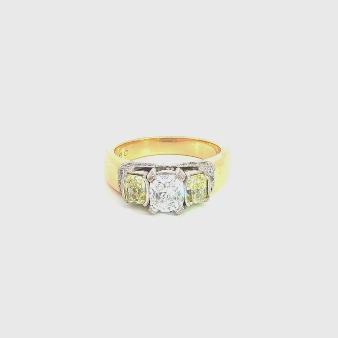 18ct yellow and white gold diamond ring featuring a 0.91ct cushion cut centre diamond with Fancy Yellow side diamonds and round diamond accents.