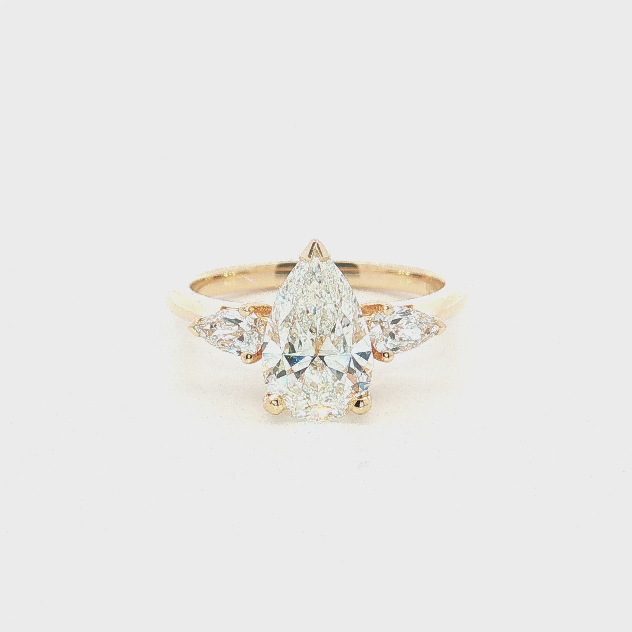 Three-stone pear diamond engagement ring in 18ct yellow gold with vertically set centre diamond and horizontal pear-shaped side stones.