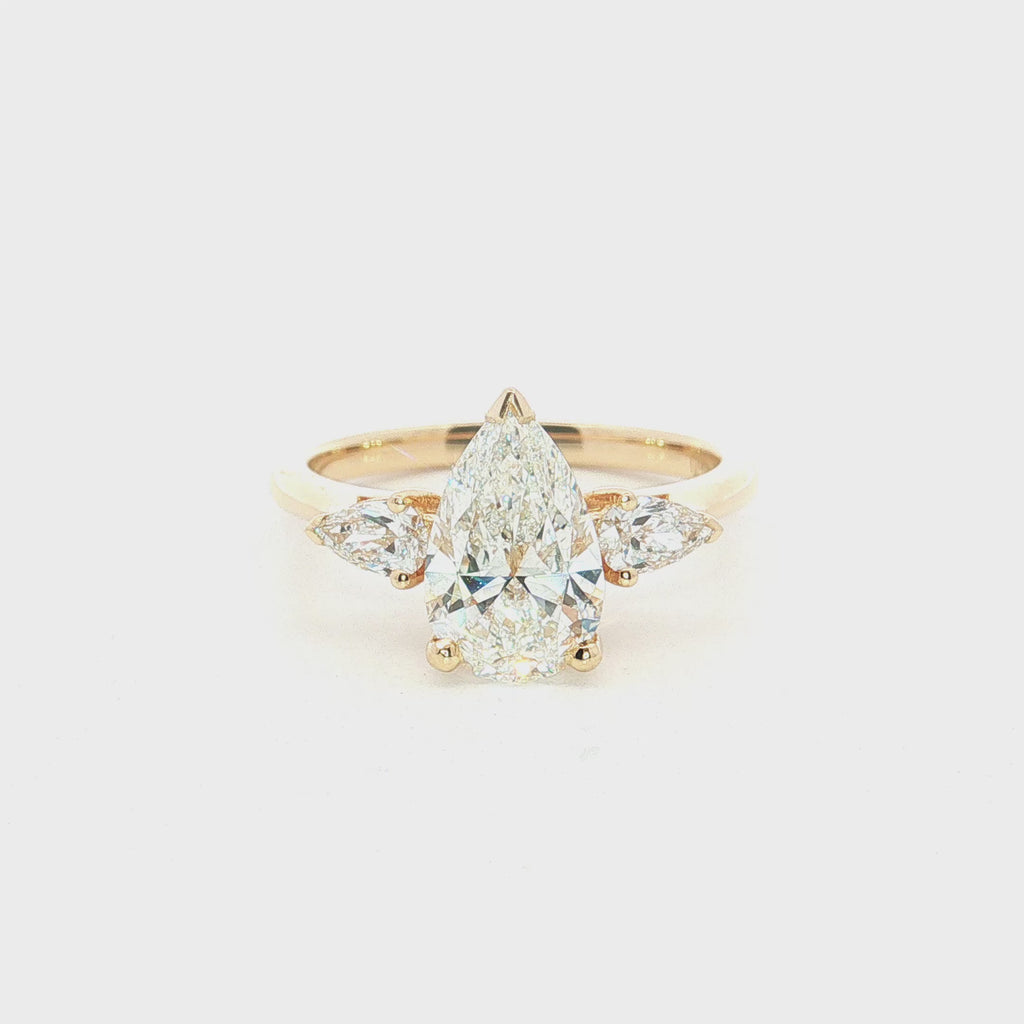 Three-stone pear diamond engagement ring in 18ct yellow gold with vertically set centre diamond and horizontal pear-shaped side stones.