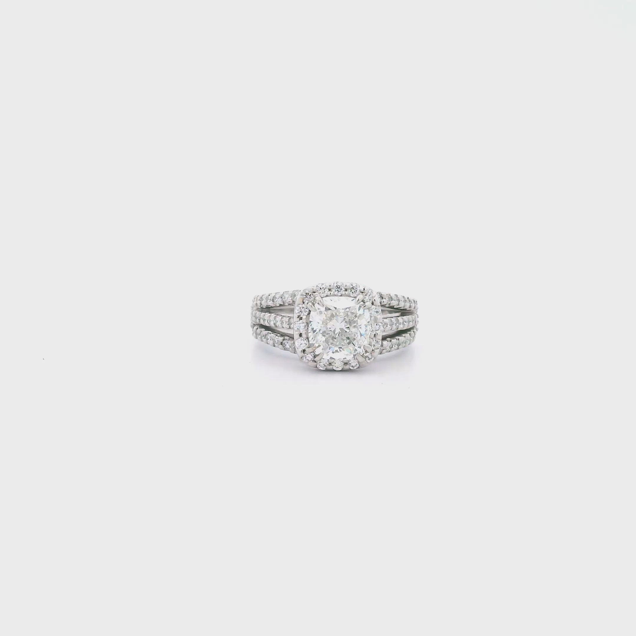 Platinum cushion cut diamond halo ring featuring a 2.00ct centre diamond with a halo surround and triple split diamond-set shoulders.