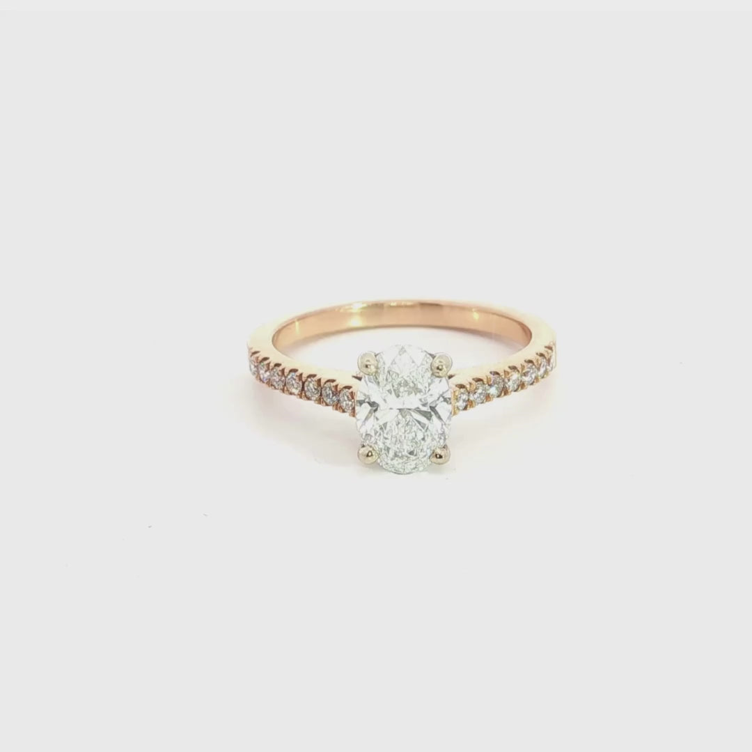 18ct rose and white gold diamond ring featuring a 1.02ct E/SI2 oval cut diamond in a white gold four-claw setting with diamond-set shoulders.