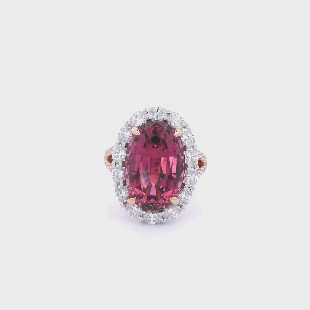 18ct rose and white gold ring featuring a 9.25ct oval pink tourmaline surrounded by a halo of diamonds, with rubies bead set into the undercarriage and split claw shoulders.