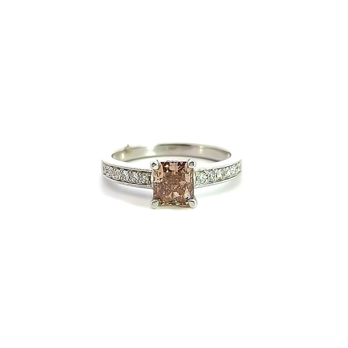 Platinum ring featuring a 1.21ct radiant cut champagne diamond with bead-set round brilliant cut diamond shoulders and millgrain detailing.