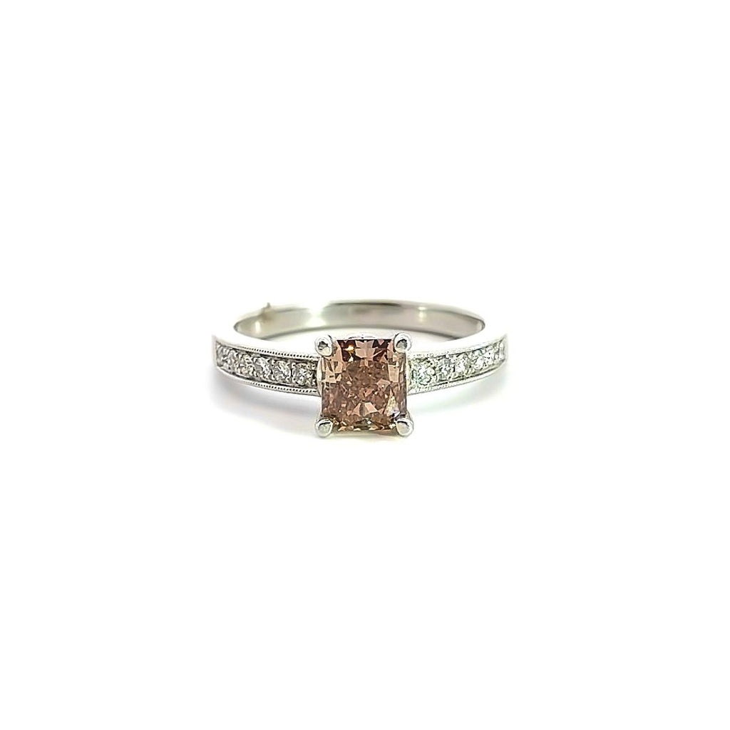 Platinum ring featuring a 1.21ct radiant cut champagne diamond with bead-set round brilliant cut diamond shoulders and millgrain detailing.