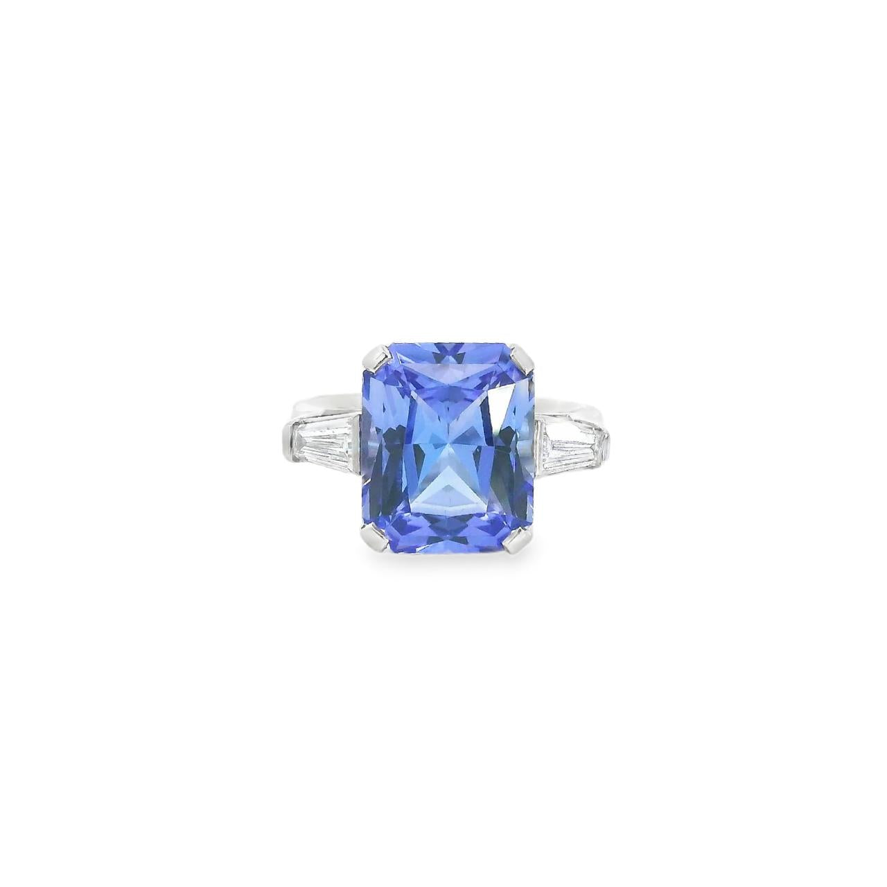 18ct white gold ring featuring a 6.99ct radiant cut tanzanite with two tapered baguette cut diamonds in a tiered three-stone setting.