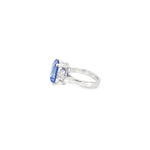 18ct white gold ring featuring a 6.99ct radiant cut tanzanite with two tapered baguette cut diamonds in a tiered three-stone setting.