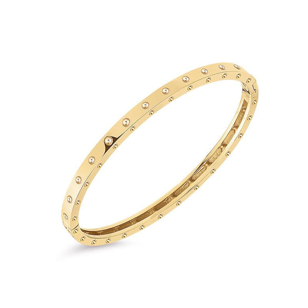 Roberto Coin Pois Moi 18ct yellow gold diamond bangle featuring polished dimple pattern on top and sides, with signature hidden ruby set inside.