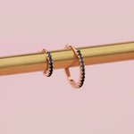 18ct rose gold black diamond huggie earrings with claw-set black diamonds around the front and inside back.