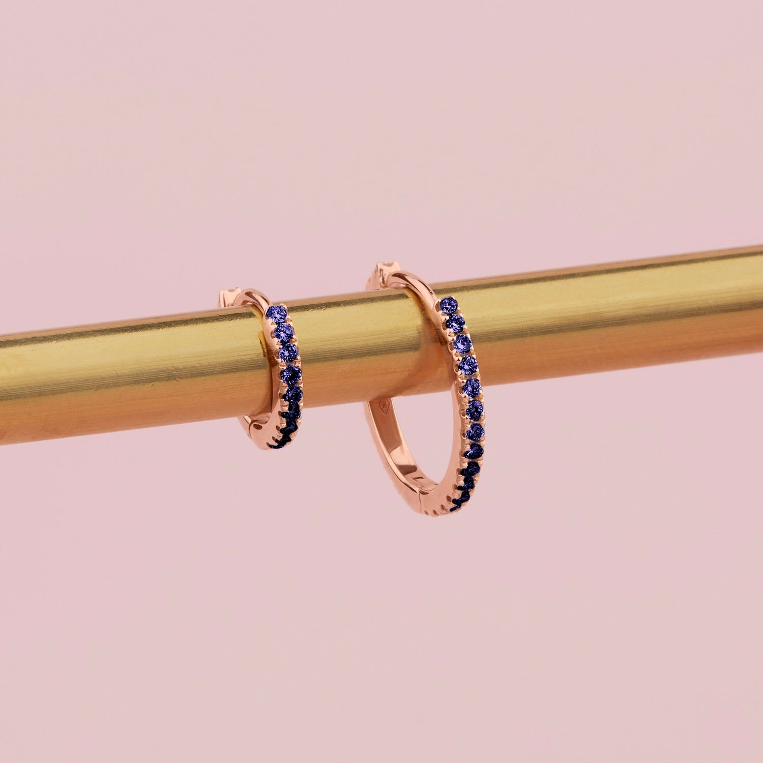 18ct rose gold sapphire huggie earrings with claw-set sapphires around the front and inside back.