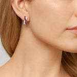 18ct white gold ruby and diamond earrings featuring a curved “X”-shaped crossover front with rubies set in black rhodium and white diamonds in alternating rows.