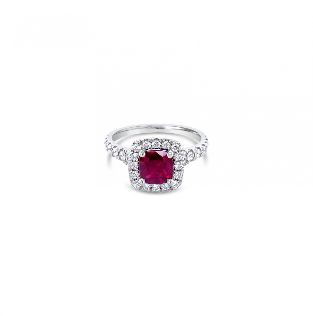 18ct white gold ring featuring a 1.06ct cushion-cut ruby in a four-claw setting with a cushion-shaped diamond halo and claw-set shoulders.