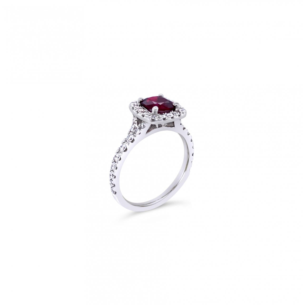 18ct white gold ring featuring a 1.06ct cushion-cut ruby in a four-claw setting with a cushion-shaped diamond halo and claw-set shoulders.