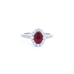 18ct white gold ruby and diamond halo ring featuring an oval ruby with a scalloped diamond surround and diamond-set shoulders, size N (resizeable).