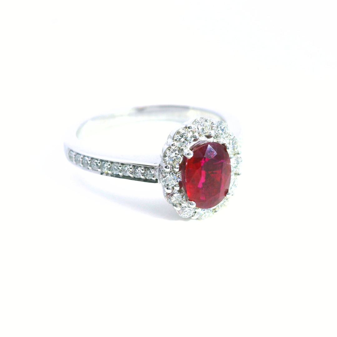 18ct white gold ruby and diamond halo ring featuring an oval ruby with a scalloped diamond surround and diamond-set shoulders, size N (resizeable).