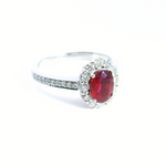 18ct white gold ruby and diamond halo ring featuring an oval ruby with a scalloped diamond surround and diamond-set shoulders, size N (resizeable).