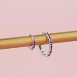 18ct white gold ruby huggie earrings with claw-set round rubies along the front and inside back, 11mm diameter, hinged with clip catch.