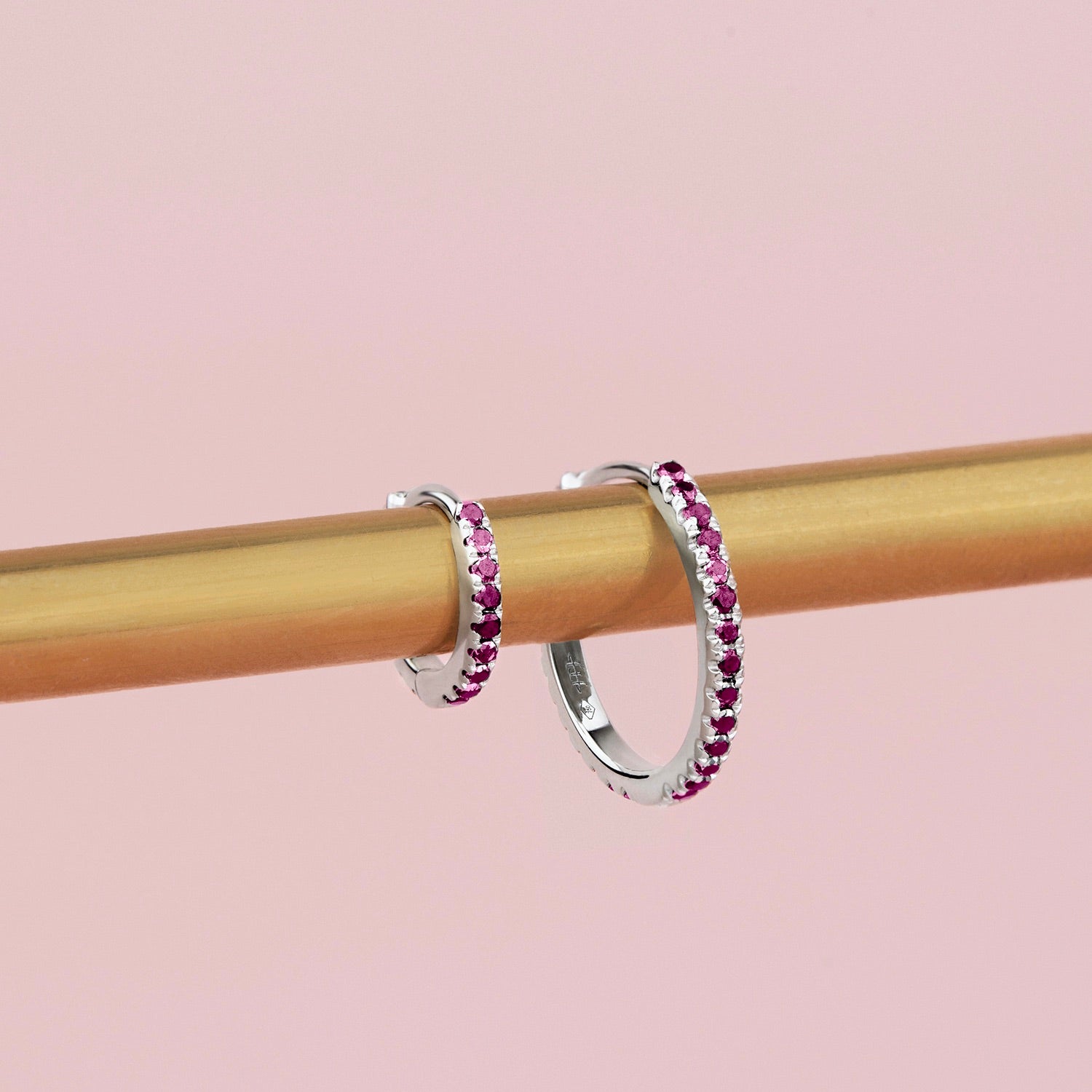 18ct white gold ruby huggie earrings with claw-set round rubies along the front and inside back, 11mm diameter, hinged with clip catch.