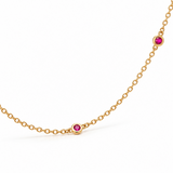 18ct yellow gold ruby station necklet featuring seven round-cut pinkish-red rubies in individual bezel settings along a fine 42cm trace chain.