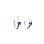 18ct white gold huggie earrings with emerald-cut sapphire and diamond set horizontally, accented by baguette and round stones, hinged with clip catch.