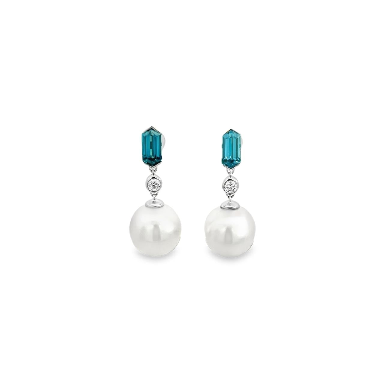 18ct white gold drop earrings featuring South Sea pearls, hexagonal-cut blue zircons, and round brilliant cut diamonds in articulated bezel settings.