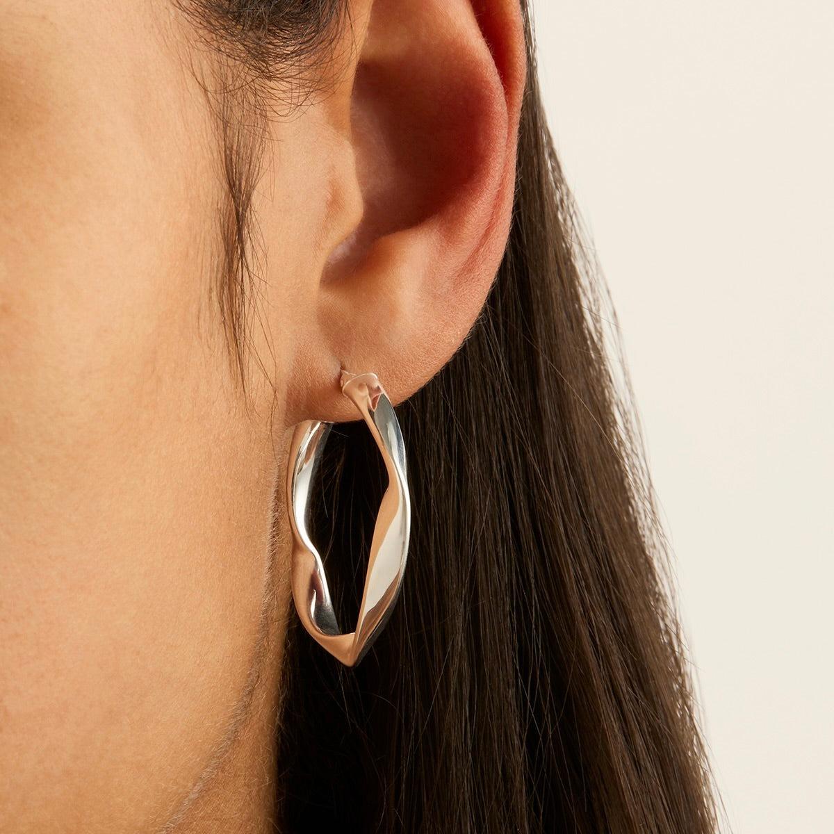 Sterling silver cushion-shaped twist ribbon hoop earrings.