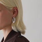 Sterling silver wavy graduated oval hoop earrings with sculptural polished finish.