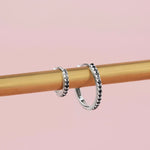 18ct white gold black diamond huggie earrings with claw-set stones around the front and inside back.