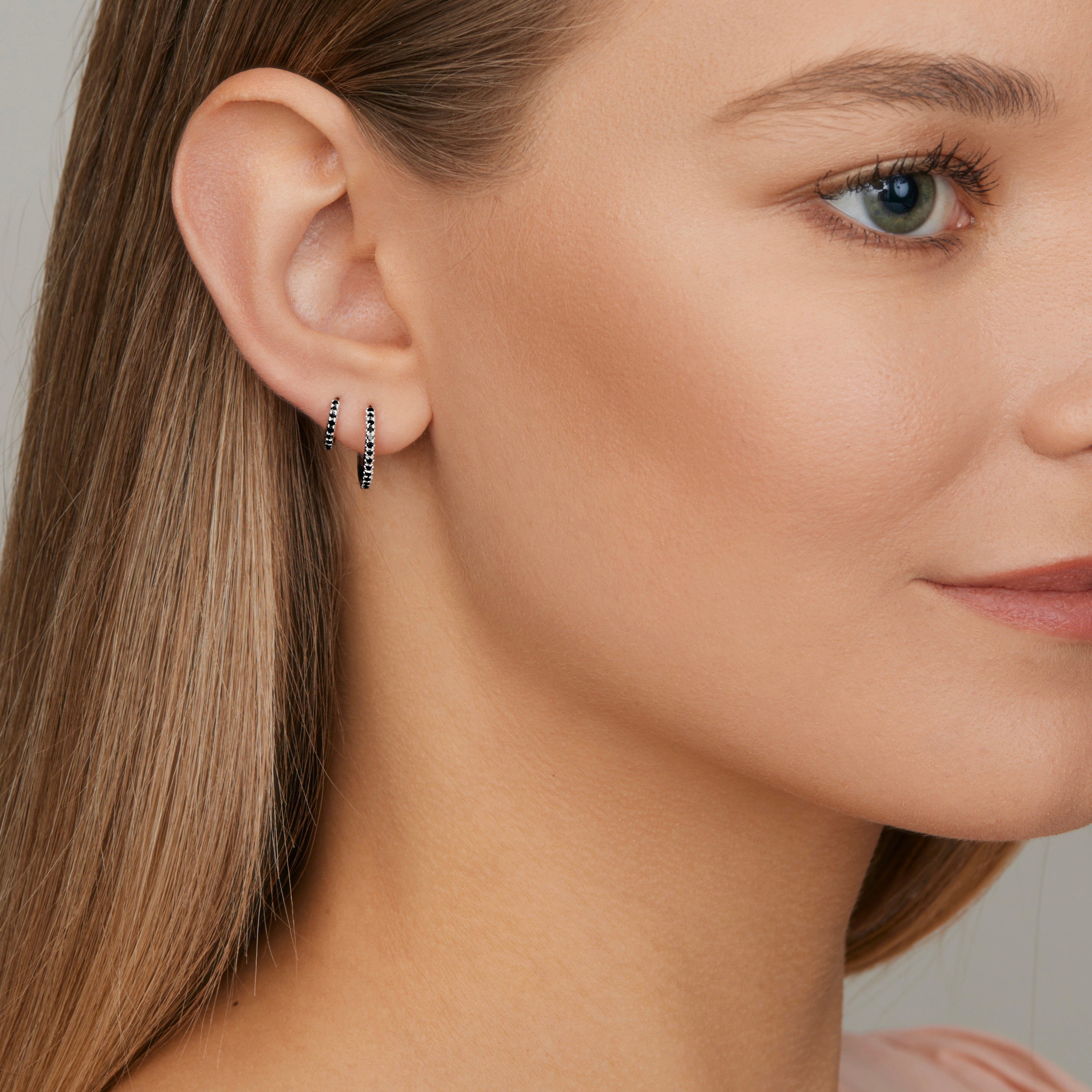 18ct white gold black diamond huggie earrings with claw-set stones around the front and inside back.