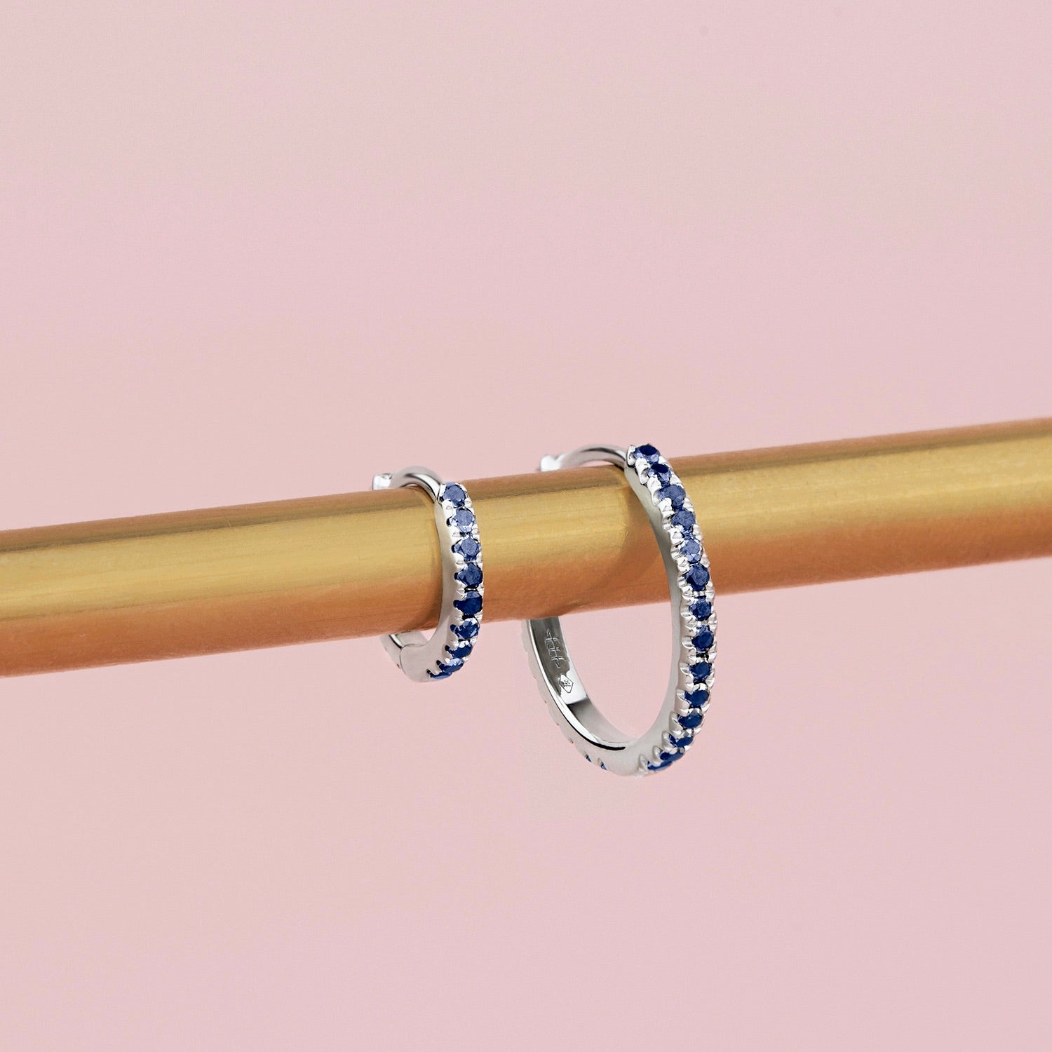 18ct white gold sapphire huggie earrings with claw-set sapphires around the front and inside back.