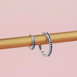 18ct white gold sapphire huggie earrings with claw-set sapphires around the front and inside back.