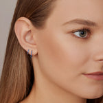 18ct white gold sapphire huggie earrings with claw-set sapphires around the front and inside back.