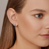 18ct white gold sapphire huggie earrings with claw-set sapphires around the front and inside back.