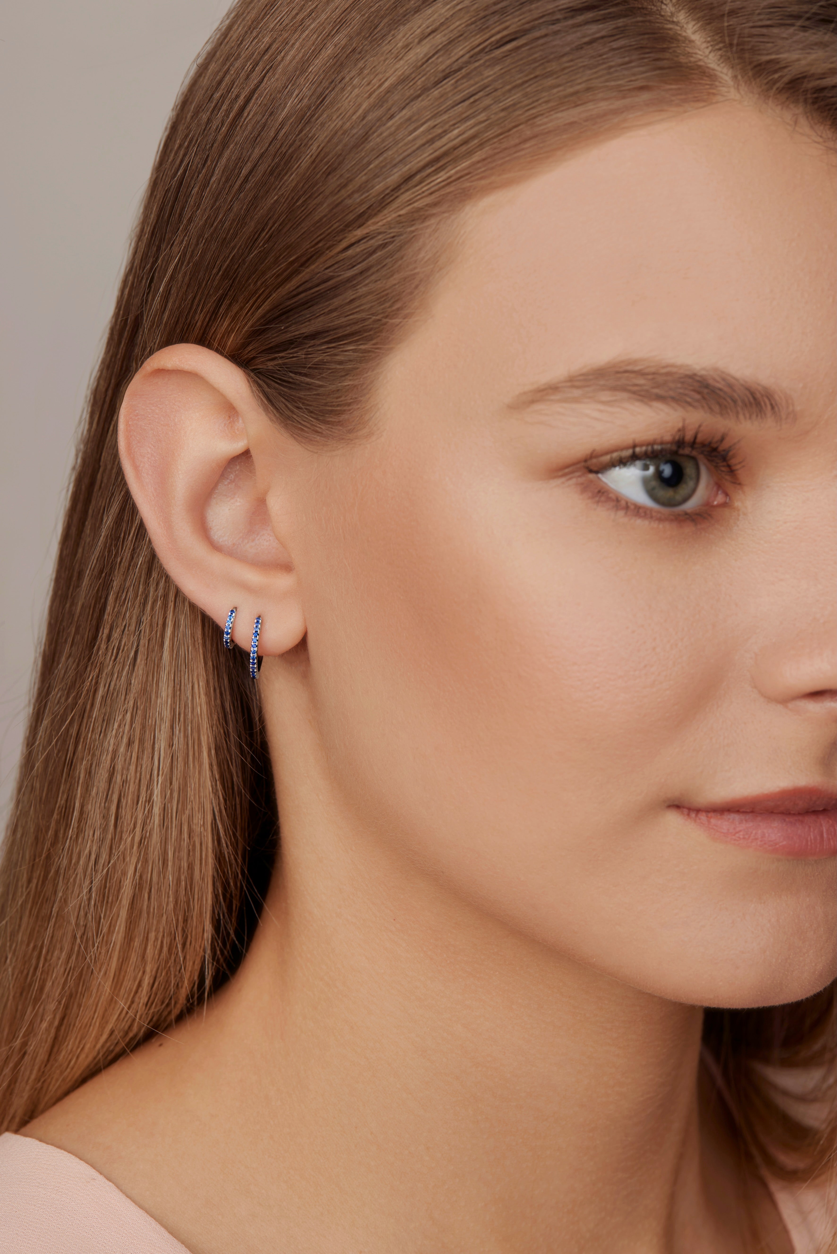 18ct white gold sapphire huggie earrings with claw-set sapphires around the front and inside back.