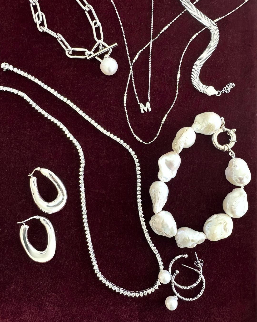 Collection of silver and pearl jewelry on a dark background