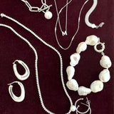 Collection of silver and pearl jewelry on a dark background