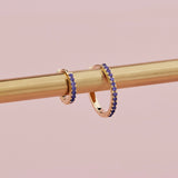 18ct yellow gold sapphire huggie earrings with claw-set blue sapphires.