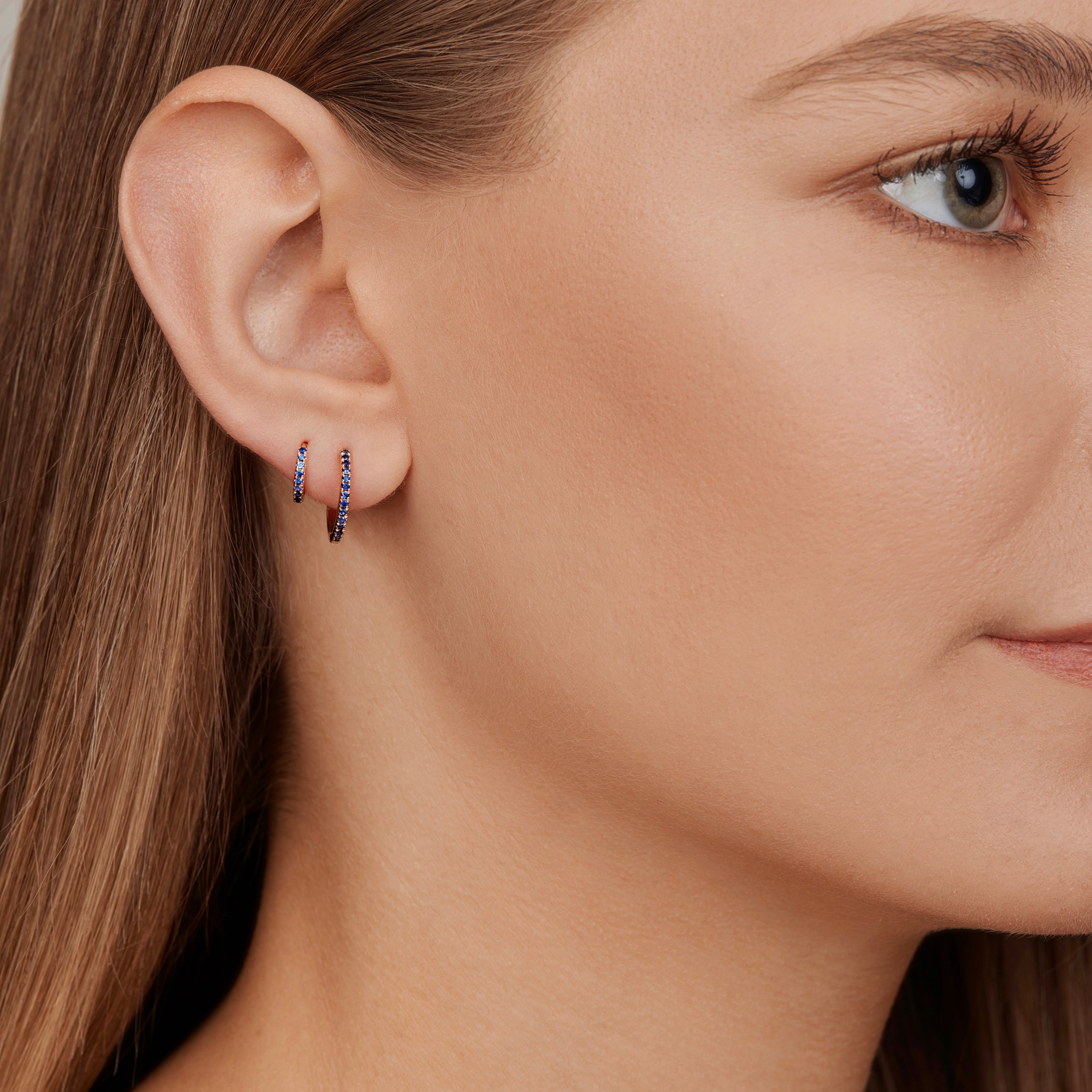 18ct yellow gold sapphire huggie earrings with claw-set blue sapphires.